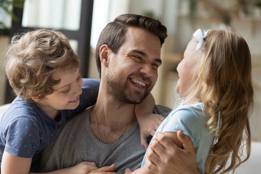 Überglücklicher junger Vater mit Sohn und Tochter